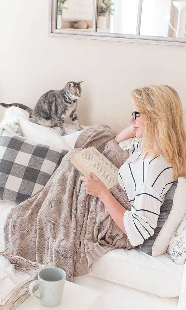 female student reading french book with a cat looking at her
