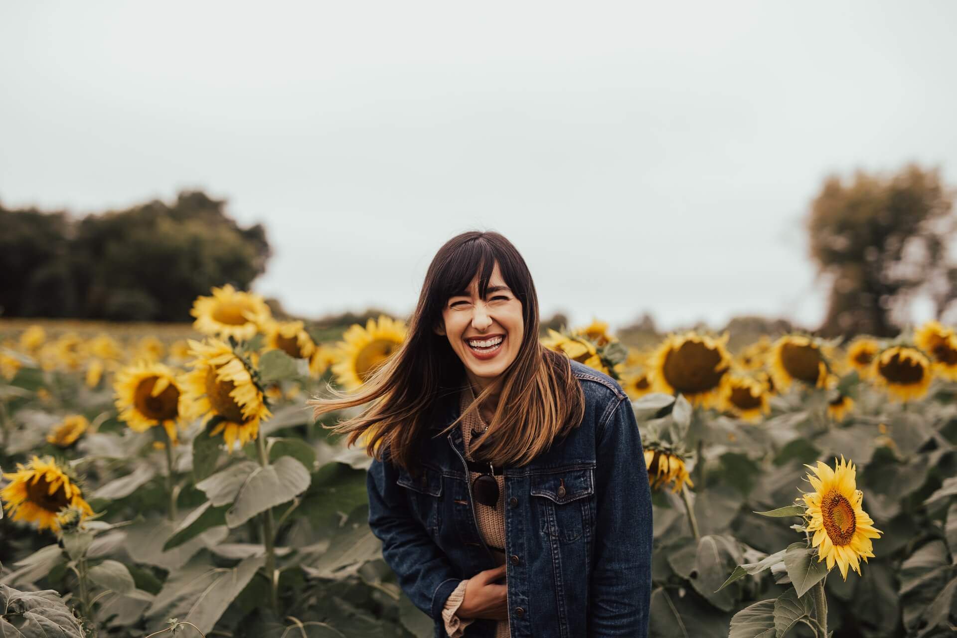 Woman in a sunflower field laughing with a French comedy