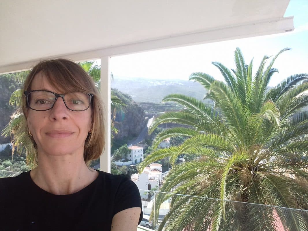 French teacher with glasses next to a palm tree